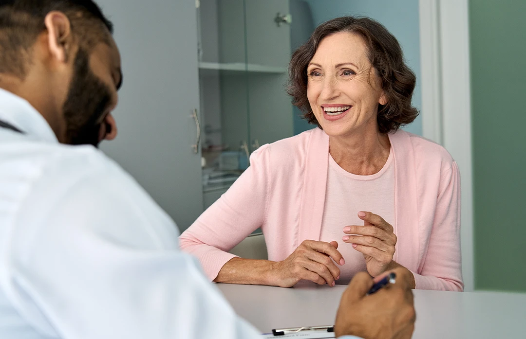 Mature-age Woman smiling, talking with doctor